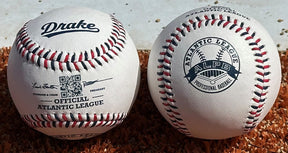 Two baseballs resting on reddish-brown sand or dirt, one white with a black Drake logo and the other white with an Atlantic League ALPS professional baseball logo.