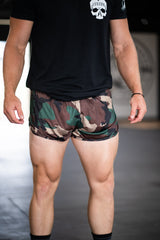 Person wearing a black t-shirt and camouflage shorts on a neutral background