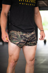 Person wearing black t-shirt with yellow text and camouflage shorts in an outdoor setting