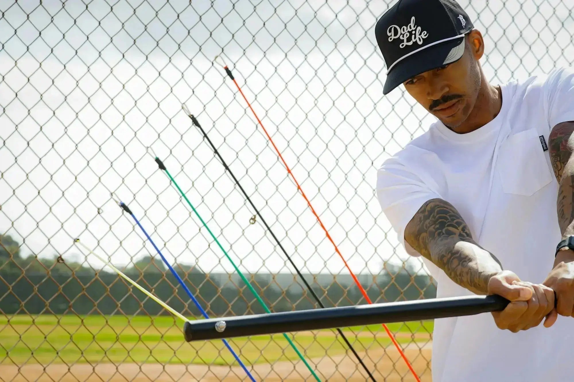 Person holding a baseball bat with colorful handles on a baseball field.