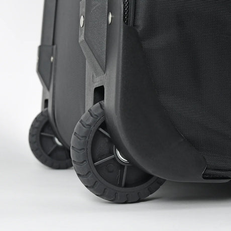 Close-up of a black hard-shell rolling suitcase showing the front wheel, protective wheel cover, and textured fabric side panel on a light gray background.